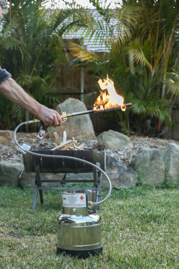 Fire starting tool flame ignited next to a firepit